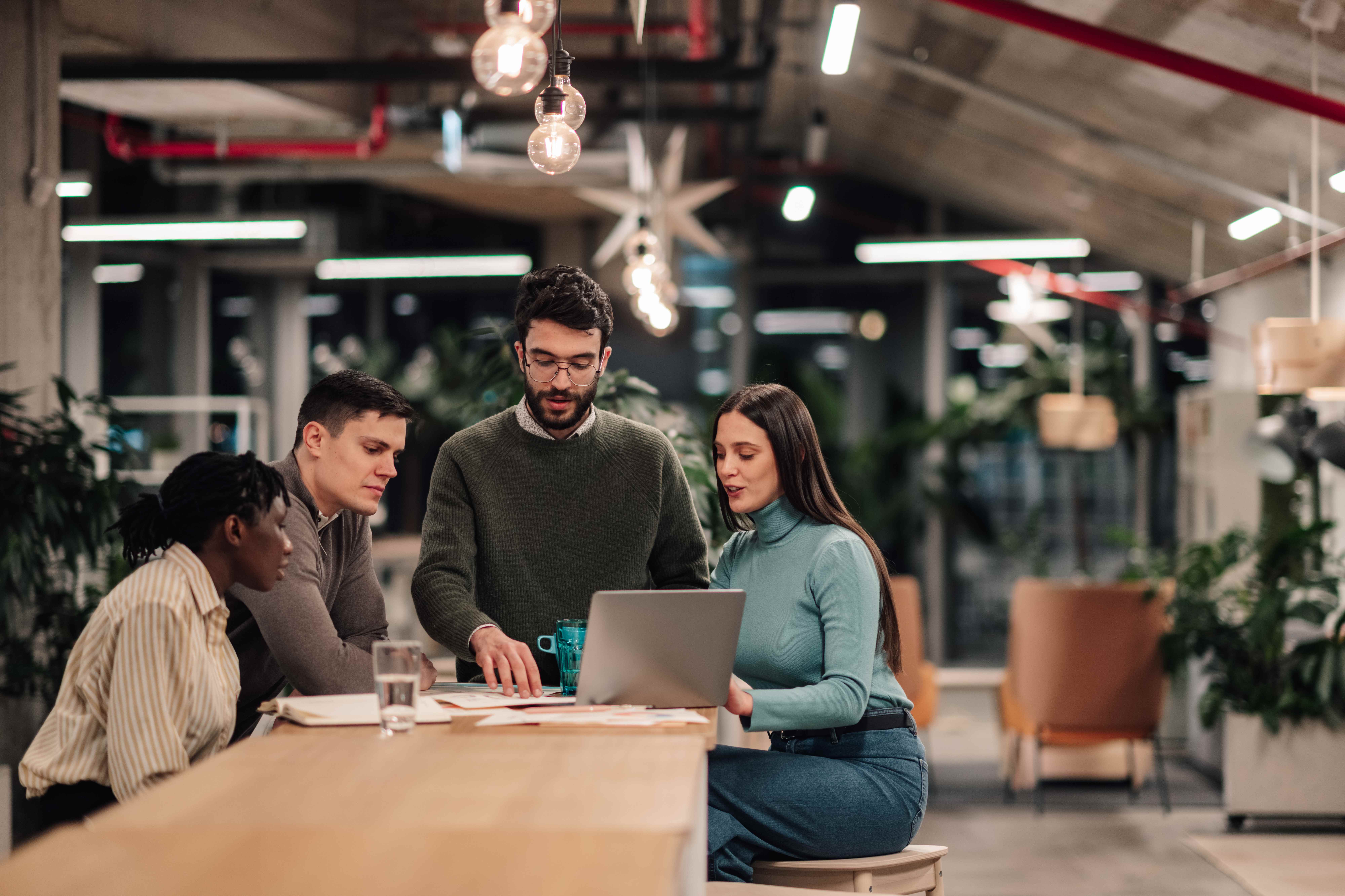 A diverse team of professionals collaborating around a laptop in a modern office